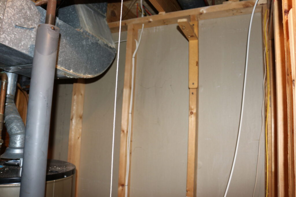 Before: The exposed furnace room wall, with nothing between the studs to help absorb sound.